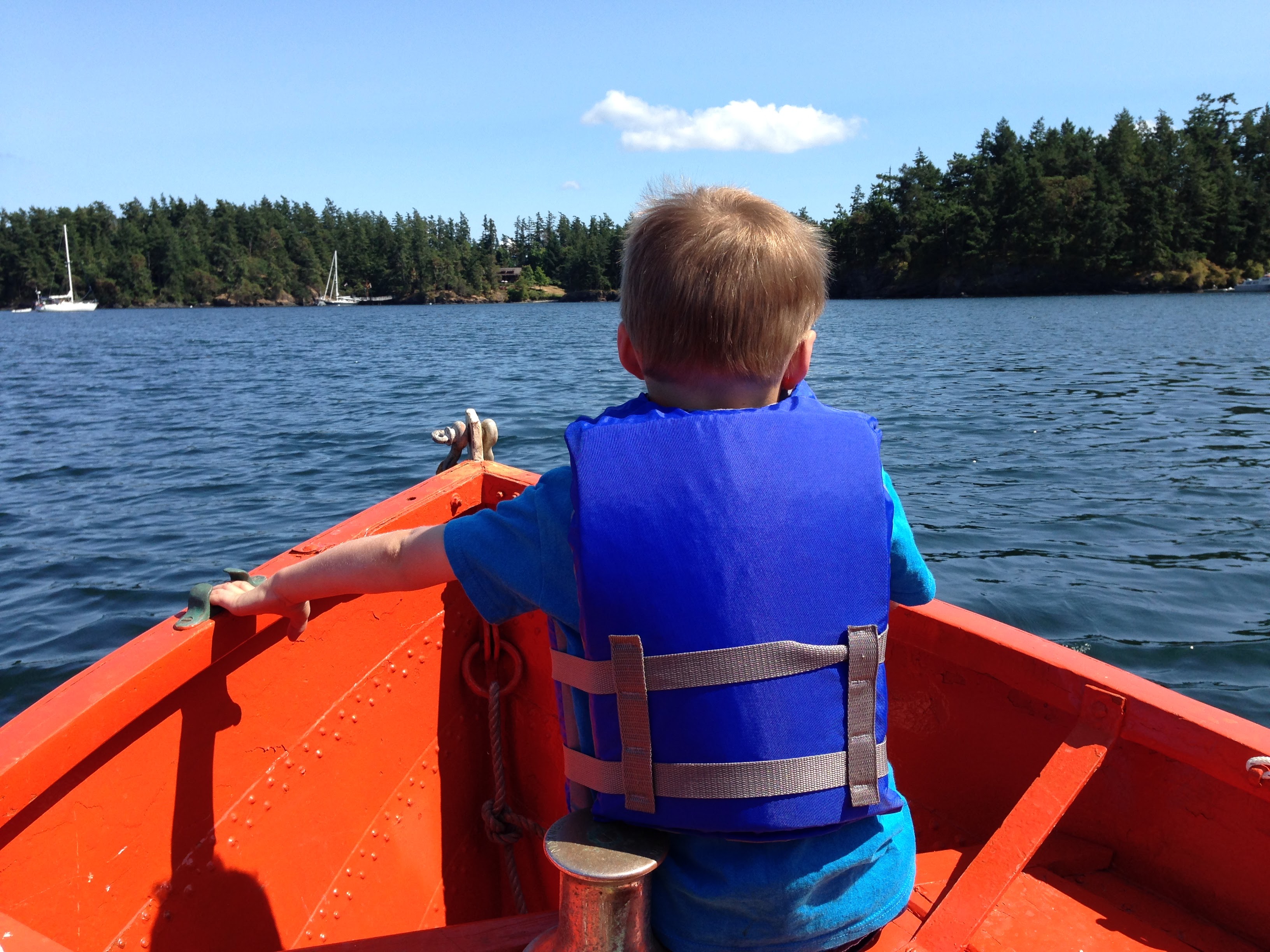 Image from behind a small child on a boat, looking off the bow