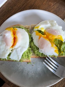 Two jammy poached eggs, cut in half through the yolk, on avocado toast.